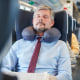 Tired businessman with neck pillow sleeping on passenger train