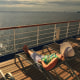 A middle aged woman in a sunbonnet relaxes on the top deck of a cruise ship during her vacation at sea