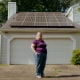 Lynn Krell stands in front of solar panels on her garage in Hattiesburg, Miss.