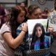Esmeralda Bravo, center, holds a photo of her granddaughter, Nevaeh, one of the Robb Elementary School shooting victims, as she is comforted by Nevaeh's cousin, Anayeli, during a prayer vigil in Uvalde, Texas, on May 25, 2022.