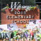 Bouquets of flowers are set in front of the Robb Elementary school brick signage