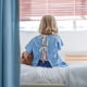 Rear view of sick girl sitting on hospital bed