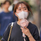 A woman uses a portable electric fan while strolling down the street with her friends in Tokyo, on June 27, 2022.