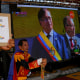 Supporters of Colombia's new President Gustavo Petro watch  his swearing-in ceremony on a giant TV screen in San Antonio, on the Venezuelan border, Sunday, Aug. 7, 2022. (AP Photo/Matias Delacroix)
