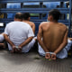 People arrested by police for having alleged links to gangs wait in zip tie handcuffs in the back of a truck to be transferred to a prison in Soyapango, El Salvador, on Aug. 16, 2022.