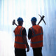 Silhouette of workers holding a hammer and a pickaxe over shoulders
