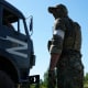 A military truck with the letter Z, which has become a symbol of the Russian military, drives past a Russian soldier standing in the road at the entrance of Mariupol, in eastern Ukraine, on June 12, 2022.