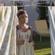 Florence Pugh as Alice, framed by sheets hanging on a clothesline, doing laundry in "Don't Worry Darling."