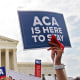A person holds at sign that reads "ACA Is Here To Stay" at the Supreme Court