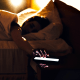Morning shot of a person lying in bed tapping phone, turning off the alarm