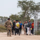 A Texas National Guard officer leads a group of migrants to be processed by U.S. Border Patrol after illegally crossing the US southern border with Mexico on Oct. 9, 2022 in Eagle Pass, Texas.