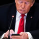 Image: President Donald J. Trump uses his cellphone as he during a roundtable discussion at the White House.