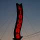 An old-fashioned, red, neon sign that reads "Liquors."