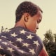 Image: Back of an Black boy wearing an American flag.