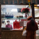 A woman waits for her food outside a restaurant in New York's Chinatown