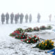 Image: Participants stand in the fog in front of wreaths at a memorial plaque during a wreath-laying ceremony at the former Buchenwald concentration camp. 