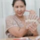 Mujer haciendo una transmisión en vivo mientras sostiene billetes en la mano