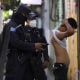A police officer searches and checks the documents of a man during a preventive patrol in search of gang members in Soyapango, El Salvador