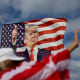 A woman walks past a flag featuring former President Donald Trump that supporters are flying near his Mar-a-Lago home on March 20, 2023 in Palm Beach, Florida. 