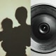 Photo illustration of a shadow of a mother holding her young child and a camera lens.