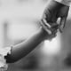 Black child holding parent's hand.