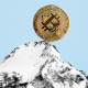 Photo Illustration: A bitcoin perched at the top of a mountain peak, on the verge of rolling down