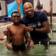 Cullen Jones standing next to a child in the pool during a swimming lesson.