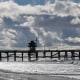 A beachgoers walks on sand a at low tide north of the pier in San Clemente, Calif, on Dec. 5, 2022. 