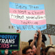 Protesters hold signs in support of transgender youth and trans access to healthcare.