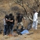 Forensic experts examine several bags of human remains extracted from the bottom of a ravine