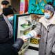 Volunteers pass out information on the Covid-19 vaccine as people receive food from the 24-hour community fridge at the Mixteca community center in Brooklyn, N.Y., on Feb. 13, 2021.