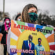 A woman holds a sign during a Latino meet and greet and literature distribution rally