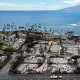 An aerial view of a recovery vehicle driving past burned structures and cars in Lahaina