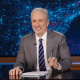 Jon Stewart at his desk on the set of The Daily Show.