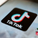 TikTok logo is displayed on a smartphone.