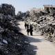 Palestinians walk through the destruction from the Israeli offensive