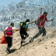 Immigrants walk through razor wire after crossing the border from Mexico, in El Paso, Texas