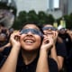 Students smile as they watch the eclipse with their glasses on.