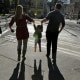 A child is lifted by her parents at a street corner in downtown Seattle.