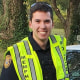 Officer Joseph McKinney smiles next to a police car.