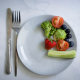 Vegetables and fruits on a plate on a light background.