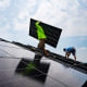 Nicholas Hartnett, owner of Pure Power Solar, carries a panel as he and Brian Hoeppner install a solar array on the roof of a home in Frankfort, Ky., on July 17, 2023.