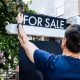 Real Estate Agent Adjusts For Sale Sign in Front Yard