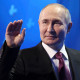 Russian President Vladimir Putin waves as he leaves a tribune after delivering a speech 