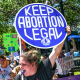 Pro abortion rights protestors hold signs saying "Keep Abortion Legal" and "End the Six Week Abortion Ban"