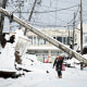 A woman walking under a downed utility pole after snow blanketed the disaster-hit area.