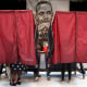 People vote in booths with an image of MLK Jr in the background in 2016