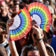 Participants wave rainbow fans during the pride parade