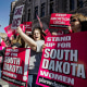 Image: Demonstrators hold up signs as they protest South Dakota's new anti-abortion law 
