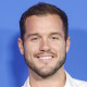 Neck up of Colton Underwood smiling in front of a light blue background